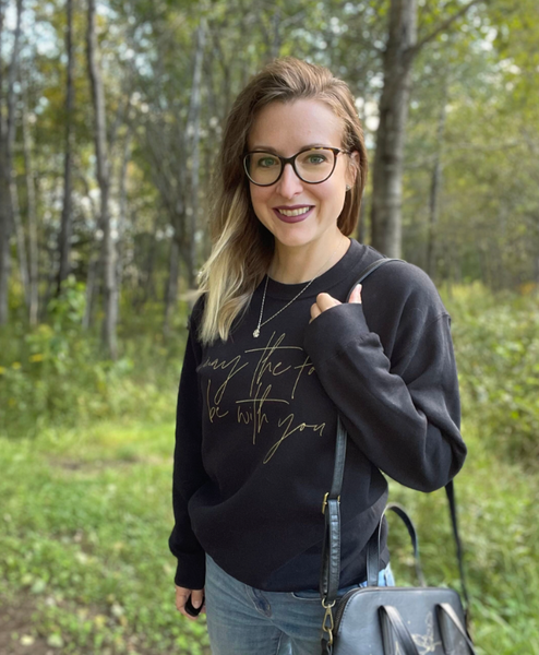 Star Wars sweatshirt May the Force be with you unisex men women shirt sweater top cotton gold scripty cursive galaxy's edge disneyland hollywood studios disneyworld gift woman wearing may the force be with you sweater top with disney crossbody bag and glasses and necklace black with gold scripty font calligraphy