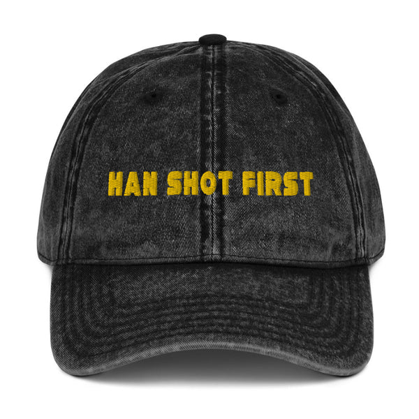 Han Shot First Hat. Black grunge washed vintage dad hat baseball cap. Yellow embroidered thread design on front. Adjustable metal buckle in back for size adjustment. One size fits all. Star Wars Han Solo inspired Harrison Ford Original Trilogy cosplay smuggler costume blaster galaxy's edge batuu star wars nite disneyland