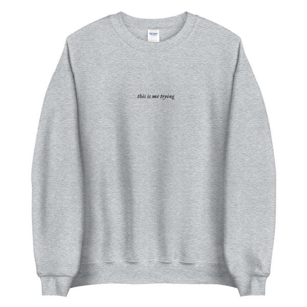 Embroidered sweatshirt in grey that says this is me trying from folklore taylor swift music album music lyrics quote. Black embroidery on gray fabric. Long sleeve pullover sweater.