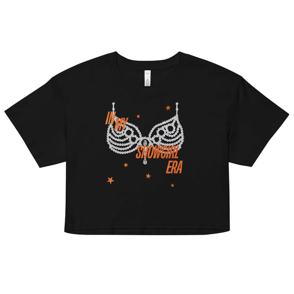 Black ‘In My Showgirl Era’ crop top with rhinestone bra graphic and orange star accents, AS Colour 4062 women’s cropped tee, relaxed fit. taylor swift graphic tee crop cropped life of a showgirl listening party movie outfit