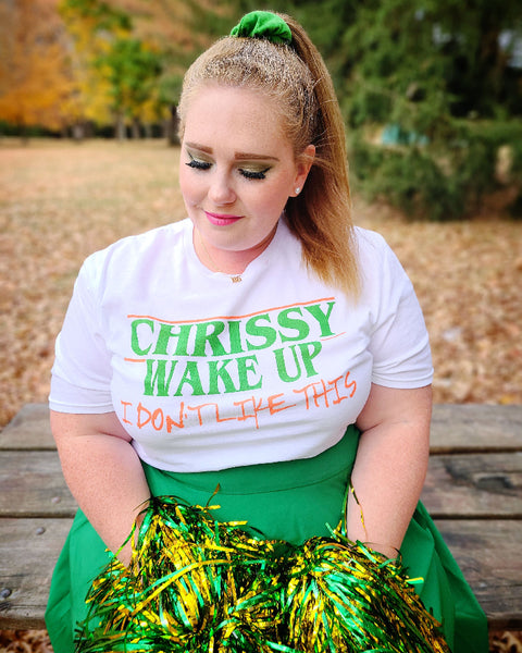 Woman wearing Chrissy Wake Up Shirt orange and green white t-shirt graphic tee unisex cotton Hellcheer cosplay costume joseph quinn stranger things eleven waffle vecna hawkins indiana comic con pom poms