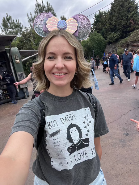 Woman wearing But Daddy I Love Him Kylo Ren Comfort Colors Shirt in grey with black and white design and little mermaid mickey ears at Galaxy's Edge Batuu theme park Disneyland, California