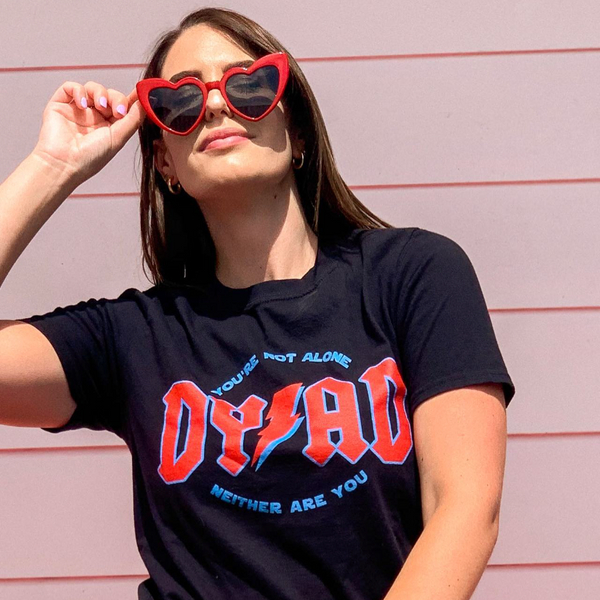 Woman wearing a black Reylo Dyad in the Force t-shirt with red and blue text, heart-shaped sunglasses, and a Gucci belt. 
