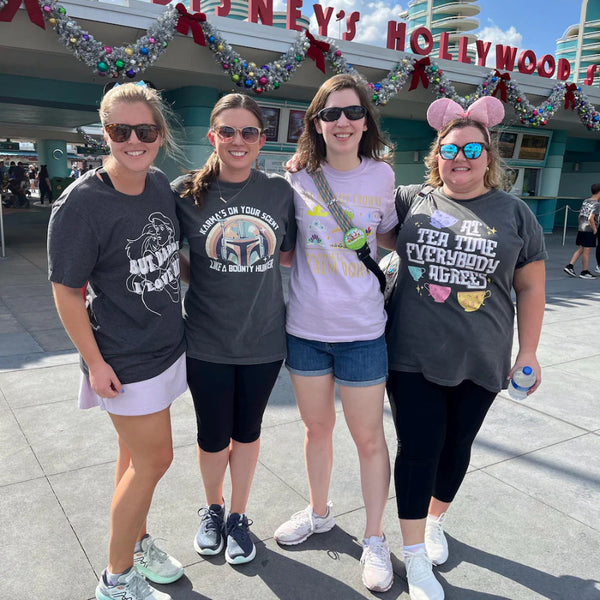 Woman wearing At Tea Time Everybody Agrees Shirt Comfort Colors Grey with Purple, Teal Blue, Pink and Yellow teacups ride design. Disney Swifties Outfit Top Eras Tour Midnights Music Lyrics Theme Park. At Disney World Hollywood Studios Christmastime in Orlando, Florida