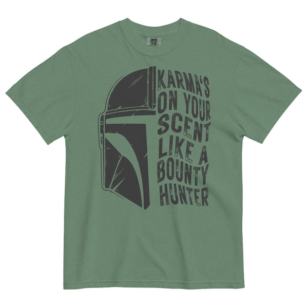 A sage green short-sleeve t-shirt with a distressed dark gray graphic of the Mandalorian helmet and the text 'KARMA'S ON YOUR SCENT LIKE A BOUNTY HUNTER' printed on the front.