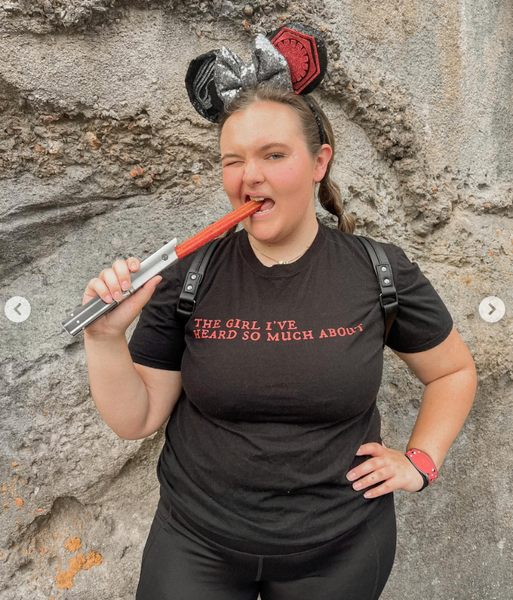 Woman eating a Star Wars churro and wearing black Kylo Ren fandom shirt styled for a Galaxy’s Edge outfit