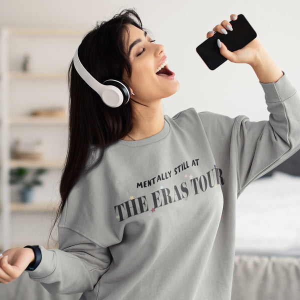 Woman wearing Mentally Still At The Eras Tour Sweatshirt colorful star for each era taylor swift swiftie sweater grey unisex cotton polyester top. Holding phone and wearing headphones singing music lyrics songs