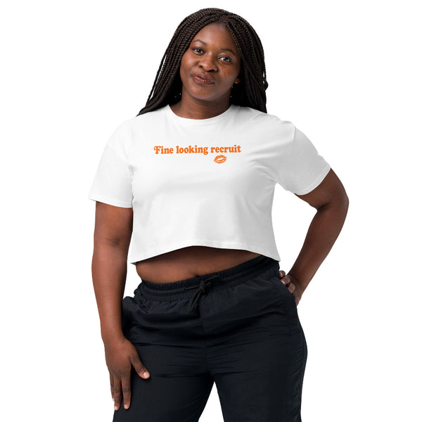 Woman wearing a white unisex graphic t-shirt with distressed orange text reading “Fine Looking Recruit” and a small orange kiss graphic.