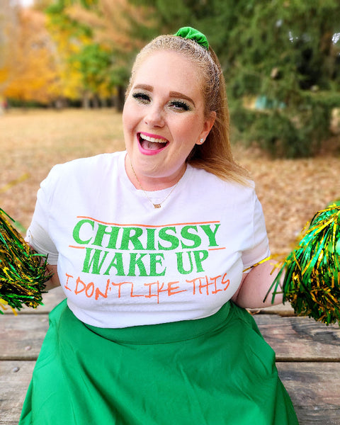 Woman wearing Chrissy Wake Up Shirt orange and green white t-shirt graphic tee unisex cotton Hellcheer cosplay costume joseph quinn stranger things eleven waffle vecna hawkins indiana comic con pom poms