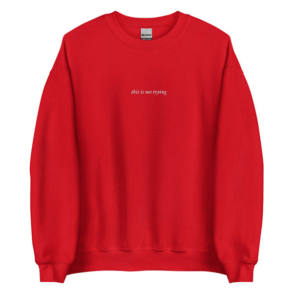 Red unisex sweatshirt with minimalist black embroidered text reading ‘this is me trying’; folklore-inspired Swiftie aesthetic crewneck. Taylor Swift music lyrics gift outfit