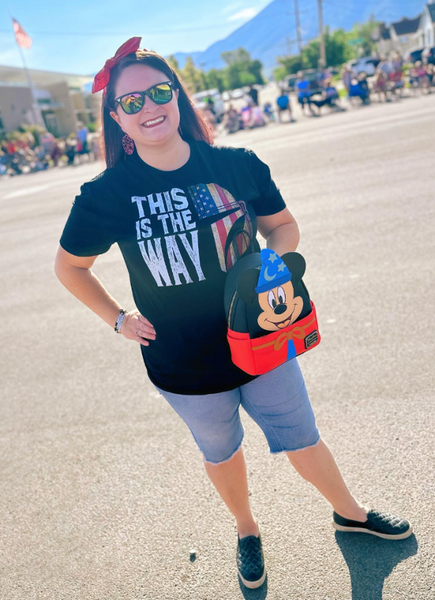 Person wearing the This Is The Way American Flag unisex t-shirt featuring an Americana-inspired Mandalorian design. Patriotic fandom shirt perfect for Fourth of July, Memorial Day, Galaxy's Edge outfits, Disneyland trips, Disney World vacations, and subtle fandom fashion.