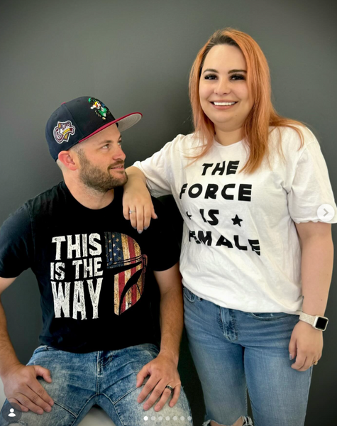 Person wearing the This Is The Way American Flag unisex t-shirt featuring an Americana-inspired Mandalorian design. Patriotic fandom shirt perfect for Fourth of July, Memorial Day, Galaxy's Edge outfits, Disneyland trips, Disney World vacations, and subtle fandom fashion.