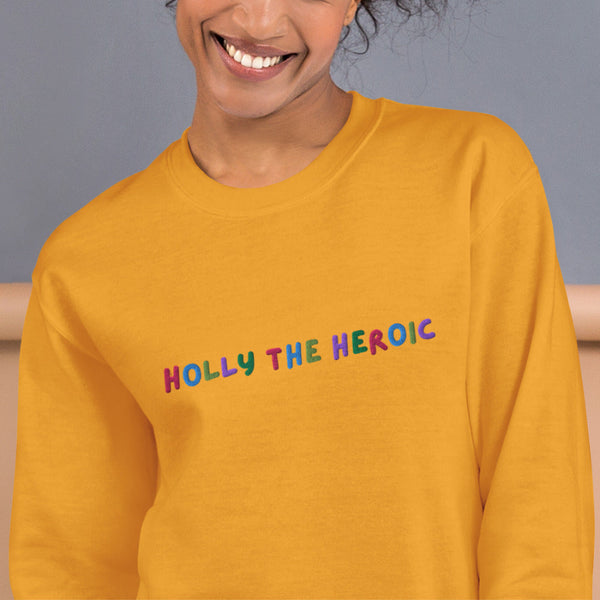 Mustard yellow unisex embroidered sweatshirt with colorful stitched text reading ‘Holly the Heroic,’ Stranger Things inspired Holly Wheeler fan design.