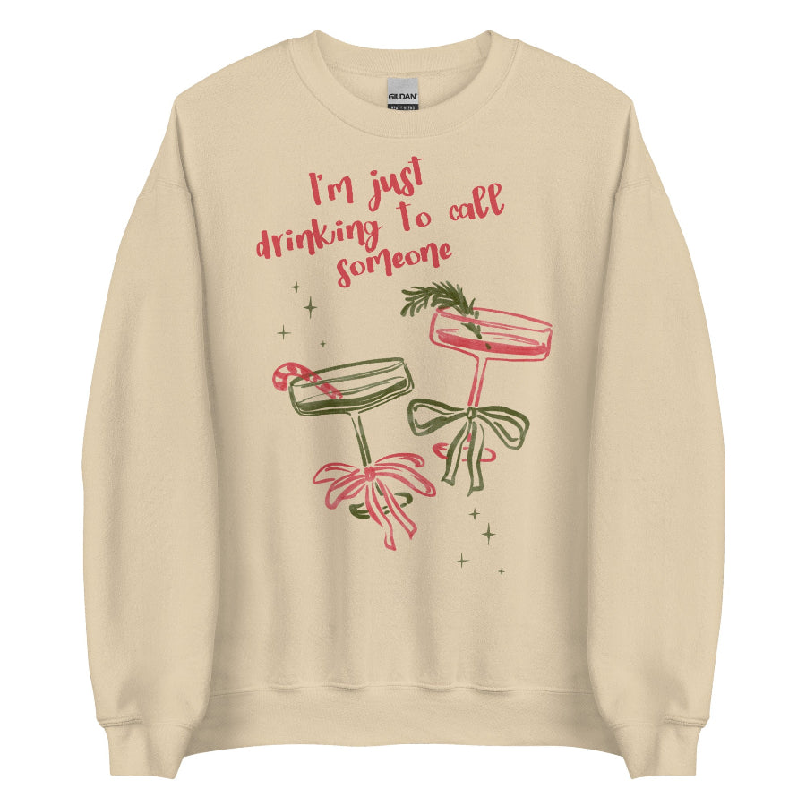 Cream unisex sweatshirt with pink and green holiday cocktail illustrations, bows, candy cane, rosemary garnish, sparkles, and text reading “I’m just drinking to call someone,” printed on cotton-poly crewneck Small-5XL. Sabrina Carpenter Christmas sweater holiday party go go juice house tour mans best friend short n sweet