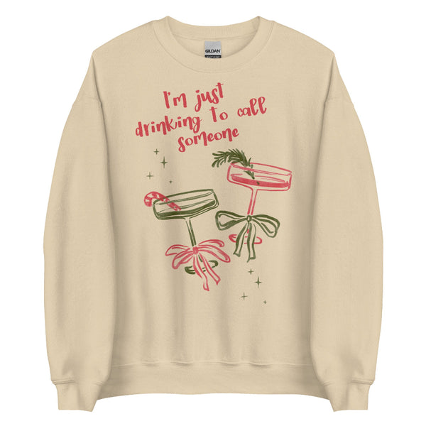 Cream unisex sweatshirt with pink and green holiday cocktail illustrations, bows, candy cane, rosemary garnish, sparkles, and text reading “I’m just drinking to call someone,” printed on cotton-poly crewneck Small-5XL. Sabrina Carpenter Christmas sweater holiday party go go juice house tour mans best friend short n sweet