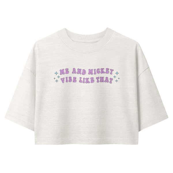 A white short-sleeve crop top t-shirt featuring the text 'ME AND MICKEY VIBE LIKE THAT' in purple bubble letters with small blue star accents, displayed on a clean white background.